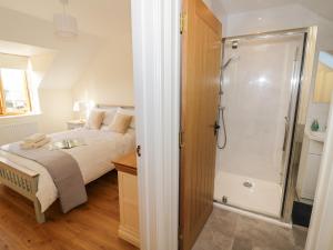 a bedroom with a bed and a shower at Granary Cottage in Southam