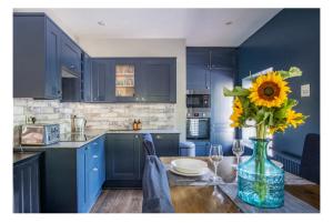 a kitchen with blue cabinets and a vase of sunflowers on a table at Apartment 1, 81 Chesterfield Road in Dronfield