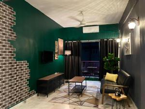 a living room with a green wall and a table at The Berlian Guesthouse - Two beedroom Apartment with Pool View in Port Dickson