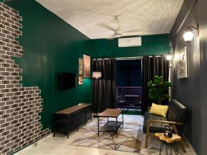 a living room with a green wall and a table at The Berlian Guesthouse - Teluk Kemang - 2 bedrooms apartmens with pool view in Port Dickson