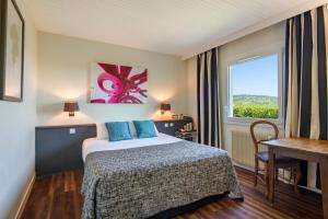 Habitación de hotel con cama y ventana en Kyriad Prestige Beaune le Panorama en Beaune