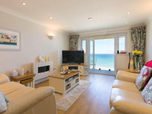 a living room with a television and the ocean at Surf and Sand in St Ives