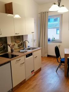 eine Küche mit weißen Schränken, einem Tisch und einem Fenster in der Unterkunft AufmLohr - Appartement mit 3 Schlafzimmern - in Leverkusen Hitdorf - Private Parkplätze vorhanden- in Leverkusen