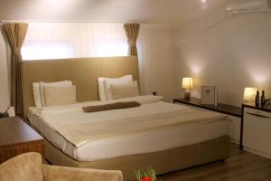 Schlafzimmer mit einem großen weißen Bett und einem Fenster in der Unterkunft Hotel Driada in Gjakove