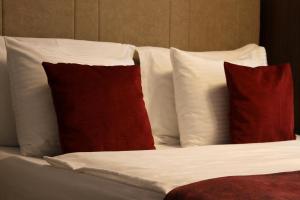 Una cama con almohadas rojas y blancas. en Hotel Driada en Gjakove