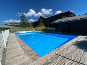 a swimming pool with a wooden deck next to a house at Appartement Samoëns, 3 pièces, 4 personnes - FR-1-624-63 in Samoëns