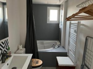 a bathroom with a tub and a toilet and a sink at La Plume Wifi Parking Un-Séjour-à-Part in Clouange
