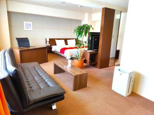 a hotel room with a bed and a couch and a bed and a room at Kurume Hotel Esprit in Kurume