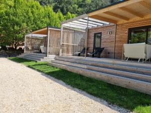 a wooden cabin with two chairs and a porch at Sportcamping & Glamping Resort Rio Vantone in Crone