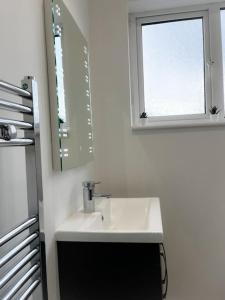 a white bathroom with a sink and a window at Incredible house for Work teams & Holiday stays in Cleethorpes