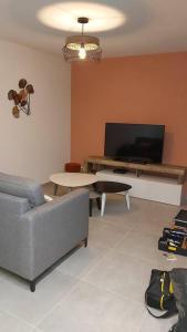 een woonkamer met een bank, een tafel en een tv bij Appartement neuf très lumineux avec parking in Argelès-sur-Mer