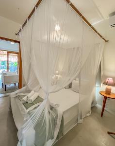 a bedroom with a canopy bed with white mosquito nets at Villa Milagre in Trancoso +14 photos