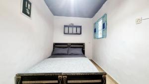 a small bedroom with a bed in a white wall at Good Vibes House Imsouane in Imsouane