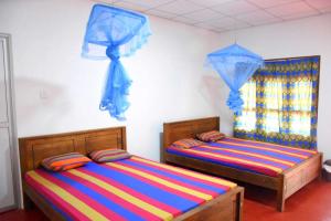 twee bedden in een kamer met blauwe parasols bij Dula Lake Resort in Anuradhapura