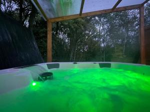 una bañera de hidromasaje con iluminación verde en un patio trasero en Cocoon Room - jacuzzi en Sémoy