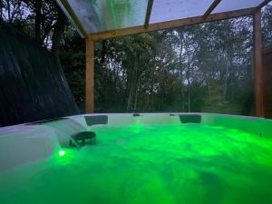 una bañera de hidromasaje con iluminación verde en un patio trasero en Cocoon Room - jacuzzi, en Sémoy