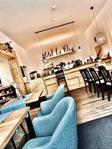 un restaurante con mesas y sillas azules y una barra en Hotel Le Filou, en Hille