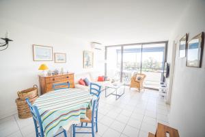 uma sala de jantar com mesa e cadeiras e uma sala de estar em LE SUNRISE Vue mer Accès Plage- Spacieux-2 Terrasses-Wifi - CONFORT -TOP PROS SERVICESConciergerieLaGrandeMotte em La Grande-Motte