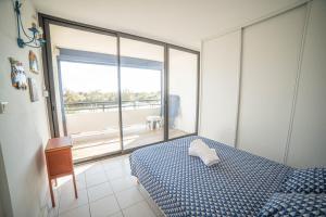 um quarto com uma cama azul e uma grande janela em LE SUNRISE Vue mer Accès Plage- Spacieux-2 Terrasses-Wifi - CONFORT -TOP PROS SERVICESConciergerieLaGrandeMotte em La Grande-Motte