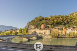 a bridge over a river in front of a city at R'Apparts Studio Street Art in Grenoble