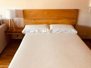 uma cama com duas almofadas brancas e uma cabeceira em madeira em Edificio El Moderno, Vigo 1.902 em Vigo