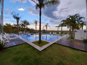 una piscina con una palmera en un patio en Cobertura Frente Mar Campeche - 3 quartos, jacuzzi, en Florianópolis