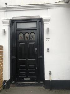 een zwarte deur aan de zijkant van een gebouw bij Self-contained Studio near Heathrow - 77VFR1 in Cranford