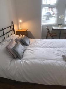 un letto bianco con cuscini sopra di Self-contained Studio near Heathrow - 77VFR1 a Cranford
