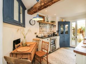 una cocina con mesa y sillas y un reloj en la pared en Cobblers Cottage, en Whitchurch