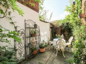 a garden with a table and a gate with plants at Cobblers Cottage in Whitchurch