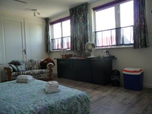 1 dormitorio con 1 cama, 1 silla y ventanas en B&B “Te Warskip bij BlokVis”, en Medemblik