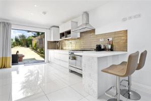 a white kitchen with a counter and chairs in it at Hampshire gated home in exclusive location in Southampton