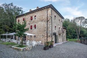 un antiguo edificio de piedra con mesas y sillas delante de él en La Locanda di Petriolo, en Monticiano