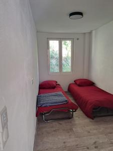 twee bedden in een kamer met rode lakens en een raam bij Superbe Rez-de-Jardin refait à neuf. in Breil-sur-Roya