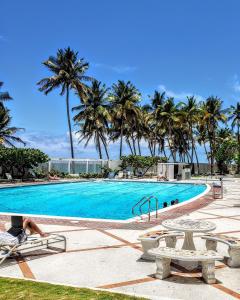 a large swimming pool with palm trees in the background at KASA Terrace Studio Breathtaking Ocean Views in San Juan