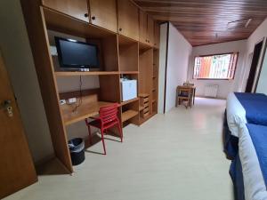 1 dormitorio con 1 cama y escritorio con TV en Summit Suítes Hotel Campos do Jordão, en Campos do Jordão