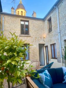 a patio with a blue couch in front of a building at Chambres d'hôtes Le Maroni in Courseulles-sur-Mer +9 photos