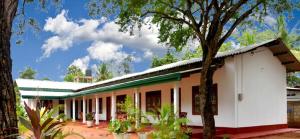 un edificio blanco con árboles delante de él en Dula Lake Resort, en Anuradhapura