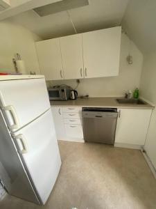 a kitchen with white cabinets and a white refrigerator at Dyrlundgaard tilbyder charmerende ferielejlighed. in Helsinge