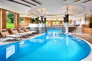 uma grande piscina azul com cadeiras no átrio do hotel em Sporthotel Ellmau in Tirol em Ellmau