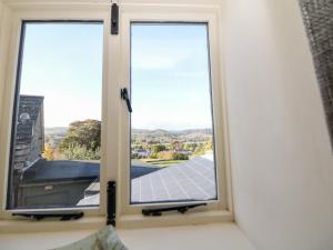 two windows in a bedroom with a view of a house at Grove Farm Barn in Matlock
