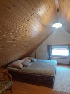 Cama en habitación con techo de madera en PENZIÓN U JANOSIKA, en Terchová