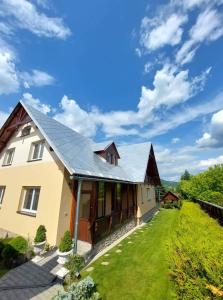 uma casa com um telhado de metal e um quintal verde em PENZIÓN U JANOSIKA em Terchová