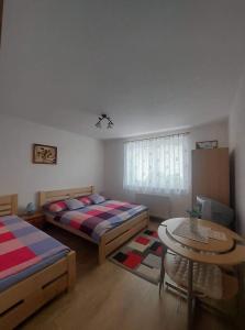 1 dormitorio con 2 camas y mesa. en PENZIÓN U JANOSIKA en Terchová