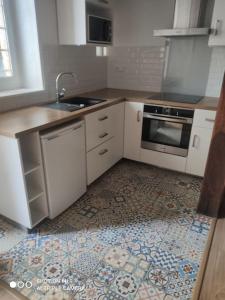 una cucina con armadietti bianchi e pavimento piastrellato di Appartement cosy au coeur d'Auvers-Sur-Oise ad Auvers-sur-Oise