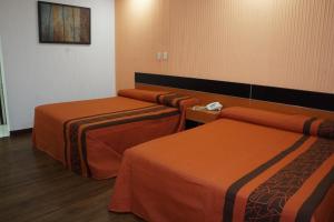 a hotel room with three beds with orange sheets at Hotel Castro in Mexico City