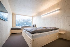 a bedroom with two beds and a large window at Revier Mountain Lodge Lenzerheide in Lenzerheide