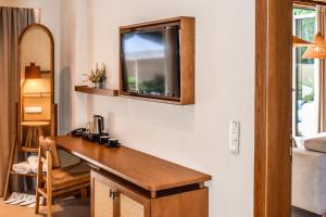a room with a desk and a television on a wall at Mandraki Village Boutique Hotel in Koukounaries