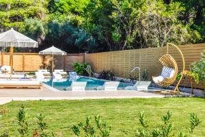 a backyard with a pool with chairs and a fence at Mandraki Village Boutique Hotel in Koukounaries