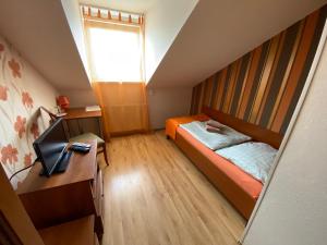 Dormitorio con cama, escritorio y TV en Penzión Alejová, en Košice